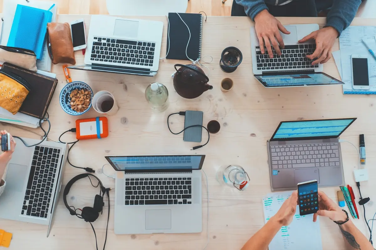 Small team working on laptops around a wooden table